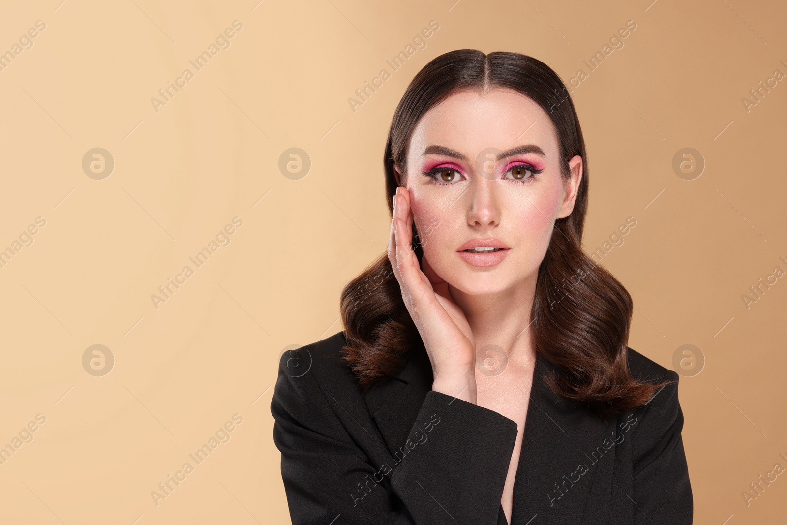 Photo of Portrait of beautiful young woman with makeup and gorgeous hair styling on beige background. Space for text