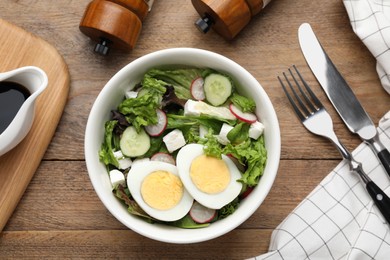 Photo of Delicious salad with boiled egg, feta cheese and vegetables served on wooden table, flat lay