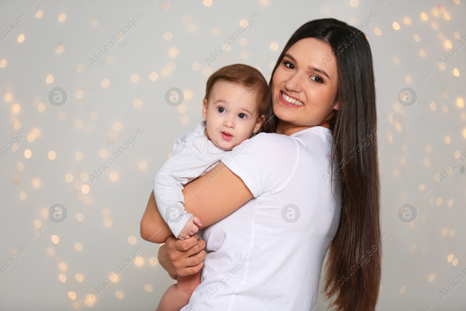 Photo of Portrait of young mother and her adorable baby against defocused lights