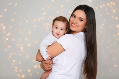 Photo of Portrait of young mother and her adorable baby against defocused lights