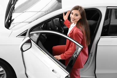 Photo of Young woman sitting in driver's seat of new car at salon