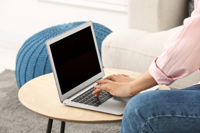 Photo of African American woman typing on laptop at table indoors, closeup