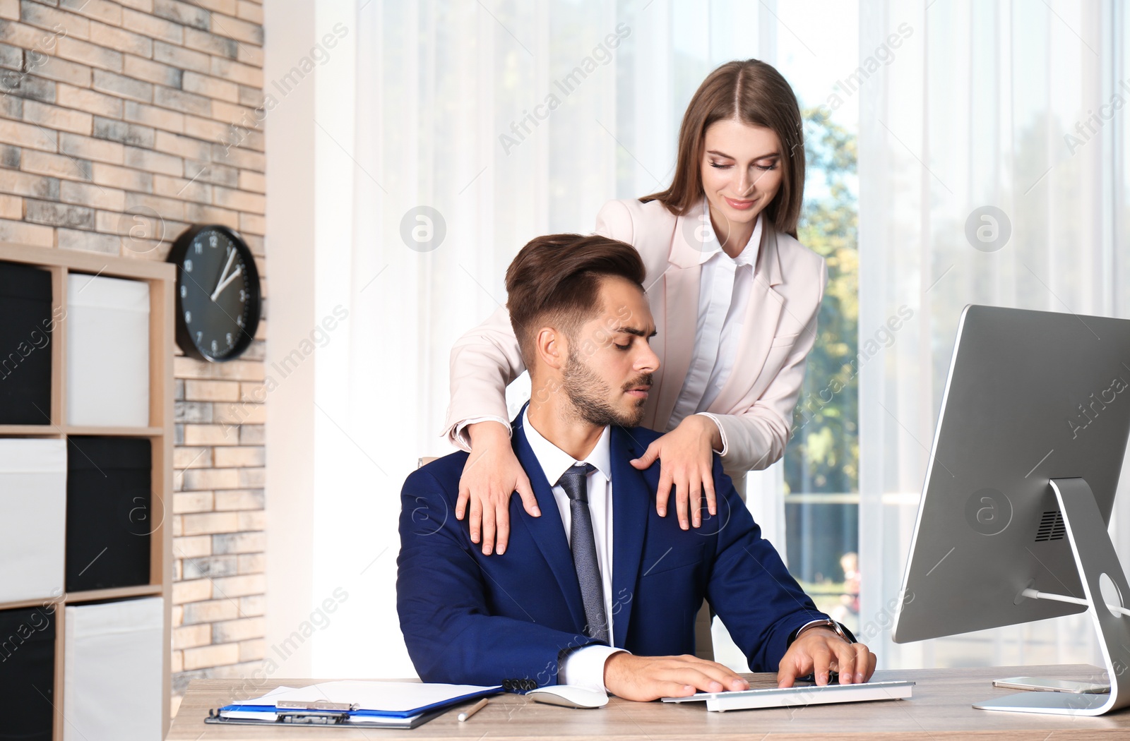 Photo of Woman molesting her male colleague in office. Sexual harassment at work