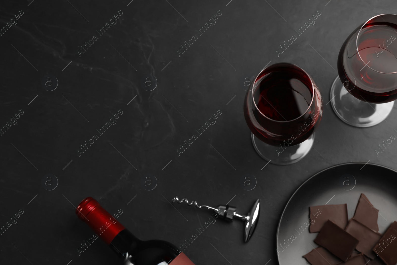 Photo of Flat lay composition with tasty red wine and chocolate on black table. Space for text