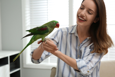 Young woman with cute Alexandrine parakeet indoors