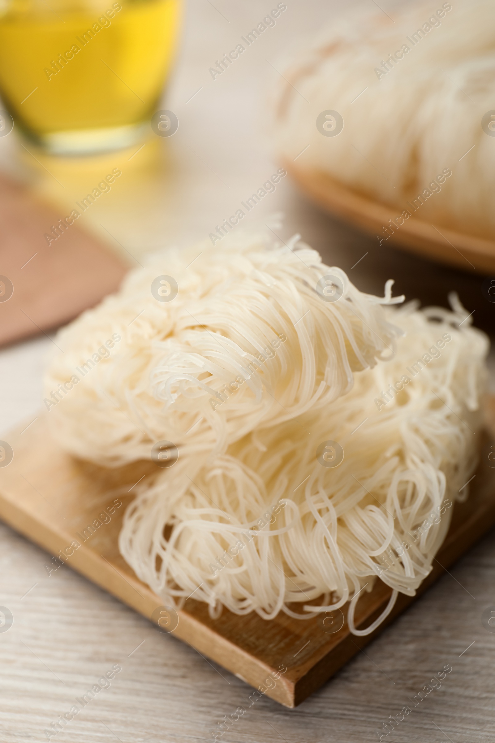 Photo of Board with uncooked rice noodles on wooden table, closeup