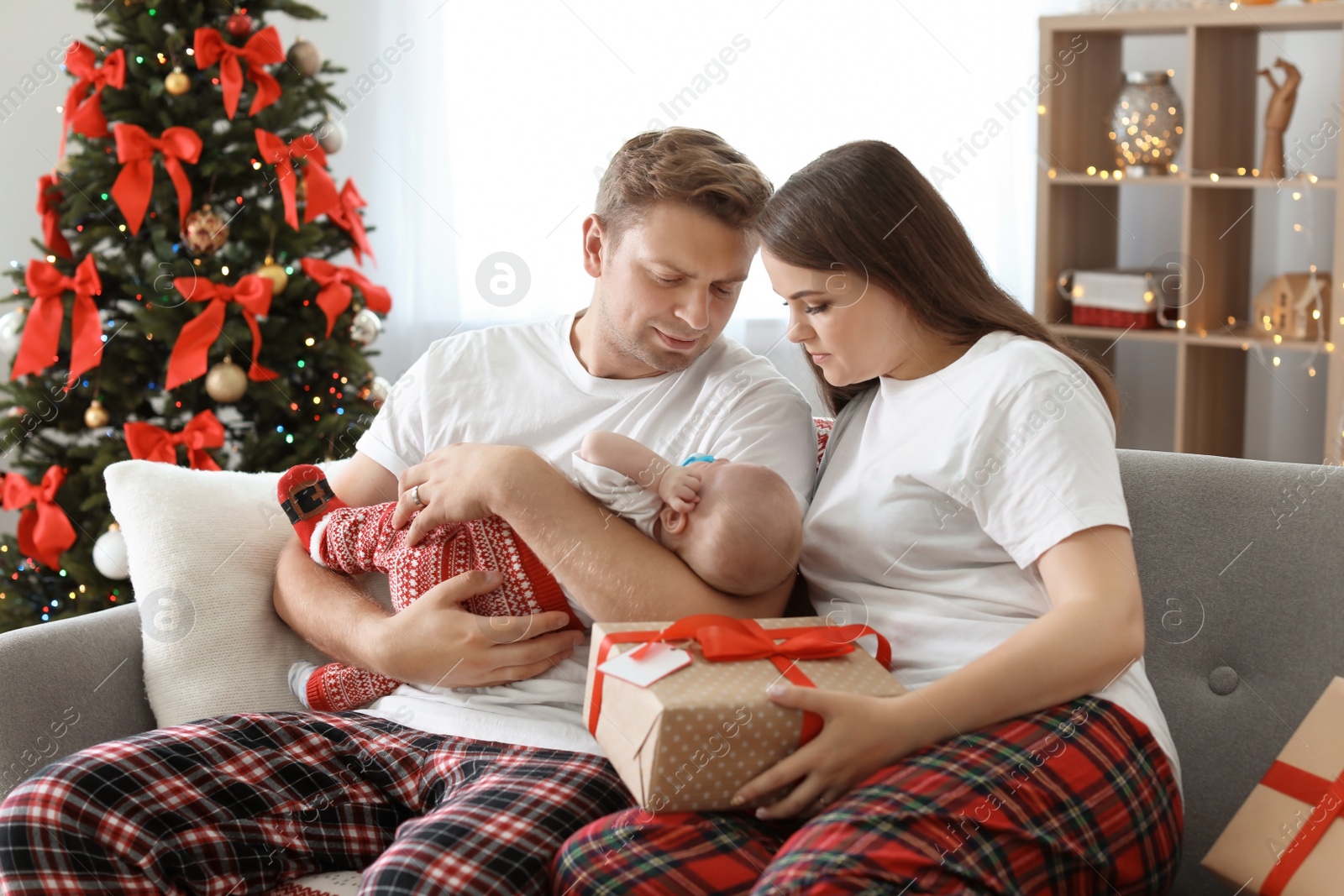 Photo of Happy couple with baby celebrating Christmas together at home