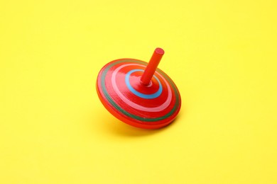 Photo of One bright spinning top on yellow background. Toy whirligig