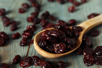 Photo of Tasty dried cranberries and spoon on blue wooden table, closeup