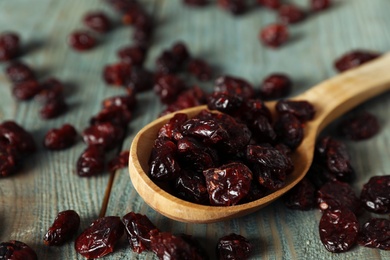 Tasty dried cranberries and spoon on blue wooden table, closeup