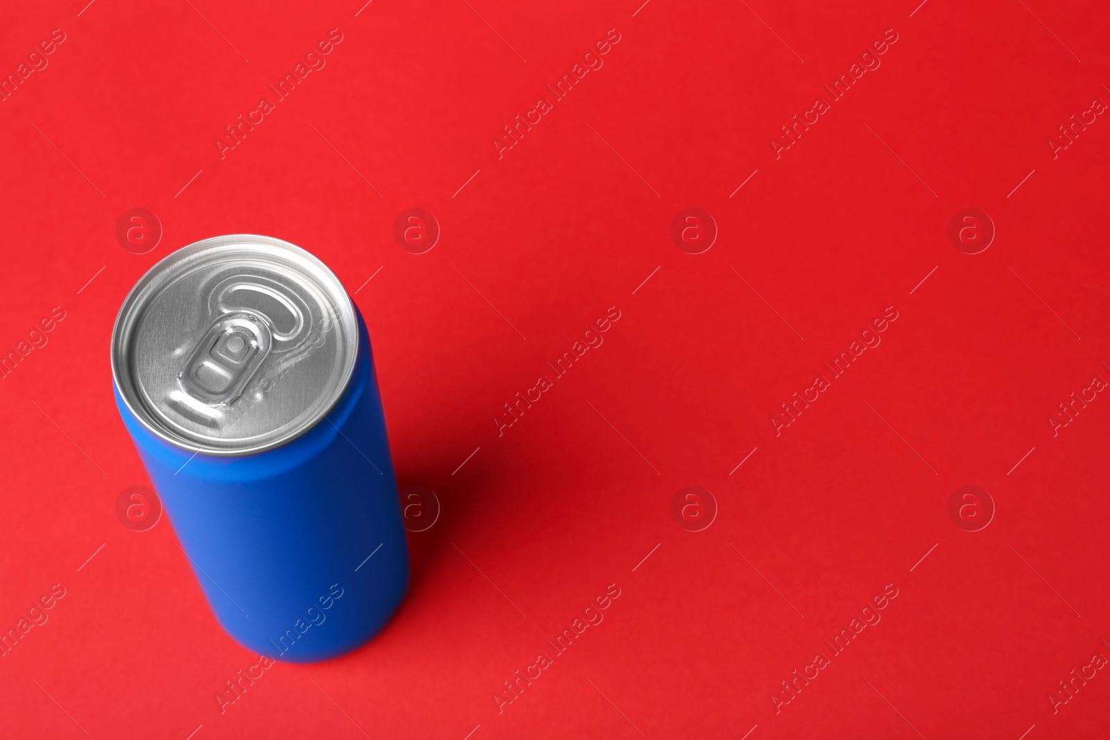 Photo of Energy drink in blue can on red background, above view. Space for text