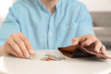 Man putting coins in wallet at table, closeup