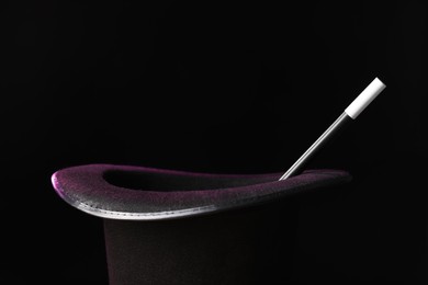 Photo of Magician's hat and wand on black background, closeup