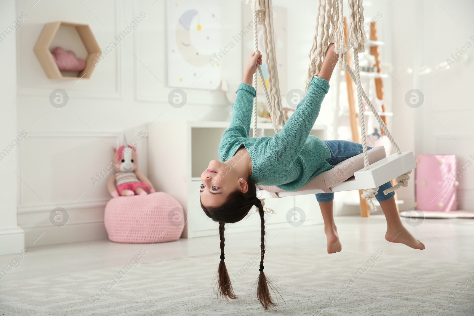 Photo of Cute little girl playing on swing at home