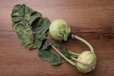 Photo of Whole ripe kohlrabies with leaves on wooden table, flat lay