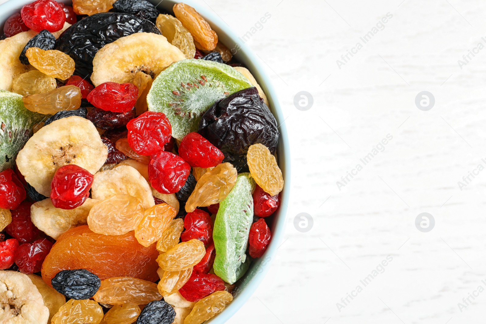 Photo of Bowl of different dried fruits on wooden background, top view with space for text. Healthy lifestyle