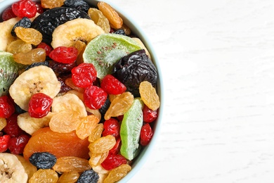 Bowl of different dried fruits on wooden background, top view with space for text. Healthy lifestyle