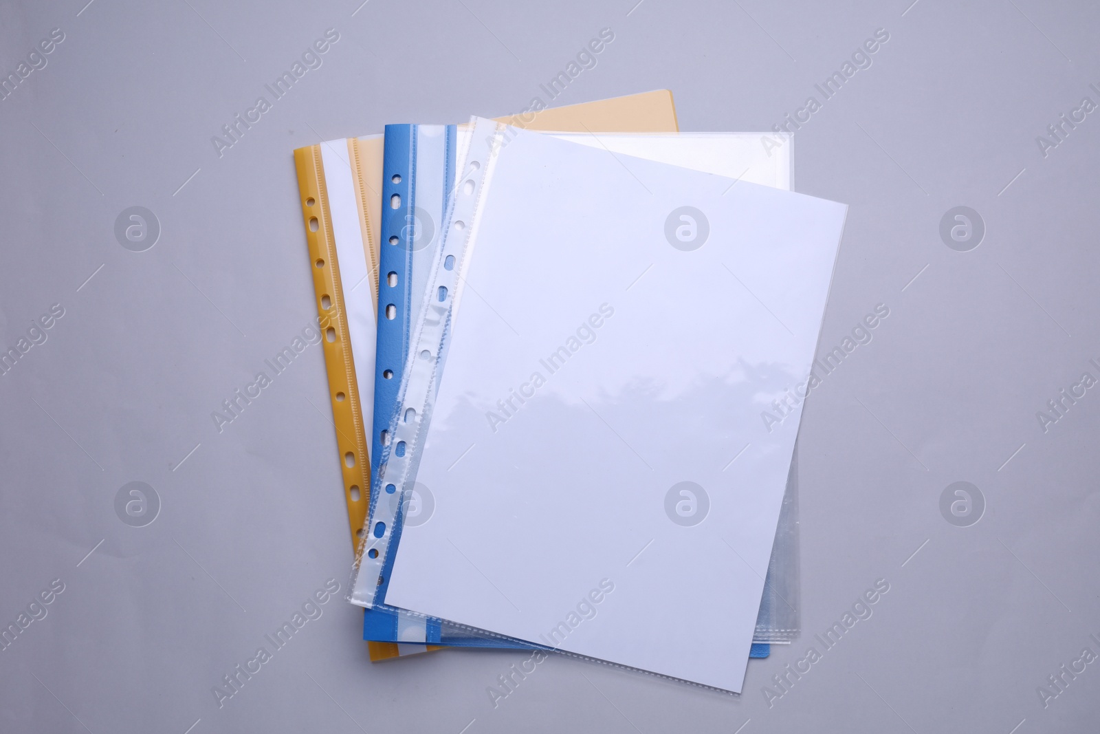 Photo of File folders with punched pockets and paper sheets on light grey background, flat lay