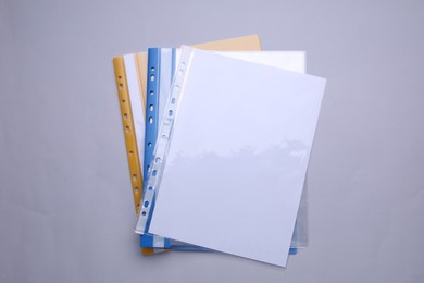 File folders with punched pockets and paper sheets on light grey background, flat lay