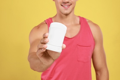 Photo of Young man with deodorant on yellow background, closeup