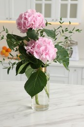 Photo of Beautiful pink hortensia flowers in vase on kitchen table