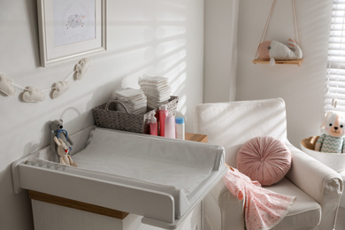 Photo of Chest of drawers with changing tray and pad in baby room. Interior design