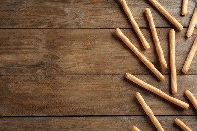 Delicious grissini sticks on wooden table, flat lay. Space for text