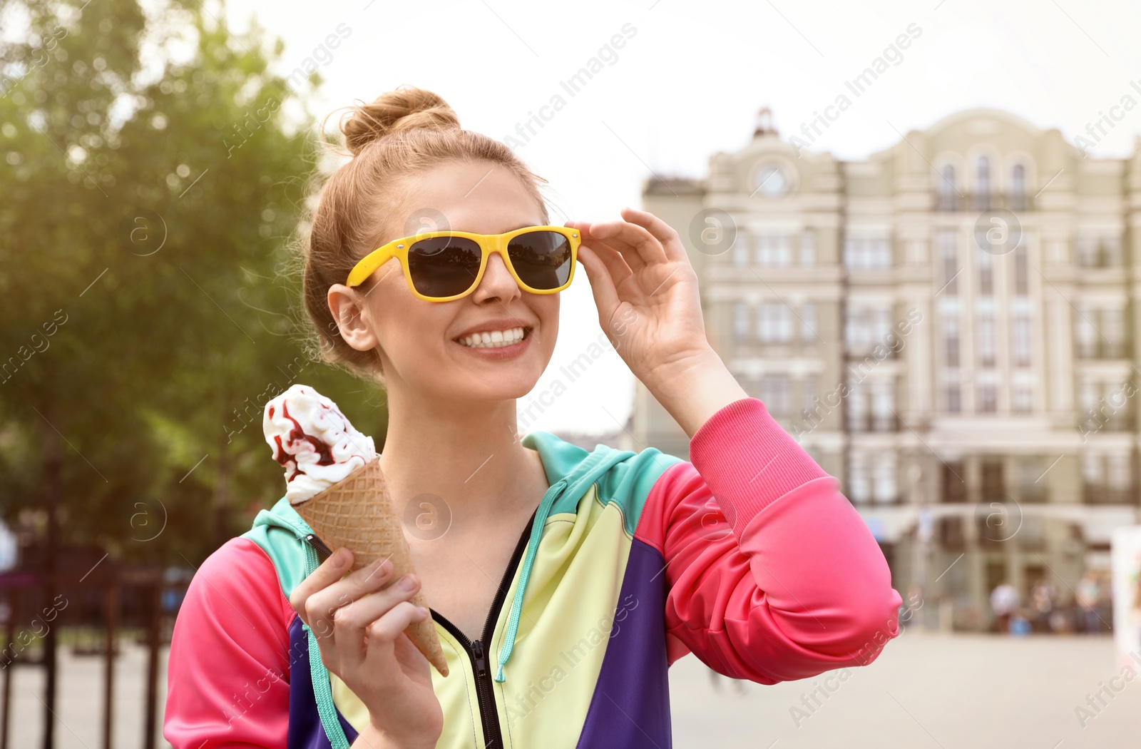 Photo of Young happy woman with ice cream cone on city street. Space for text