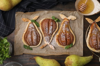 Delicious pears baked in puff pastry with powdered sugar served on wooden table, flat lay