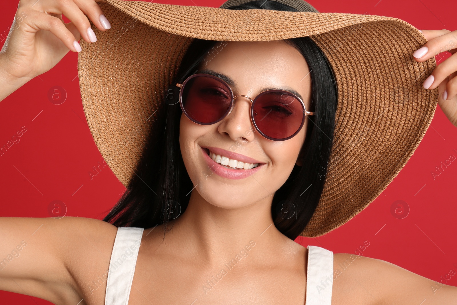 Photo of Beautiful woman wearing sunglasses on red background, closeup