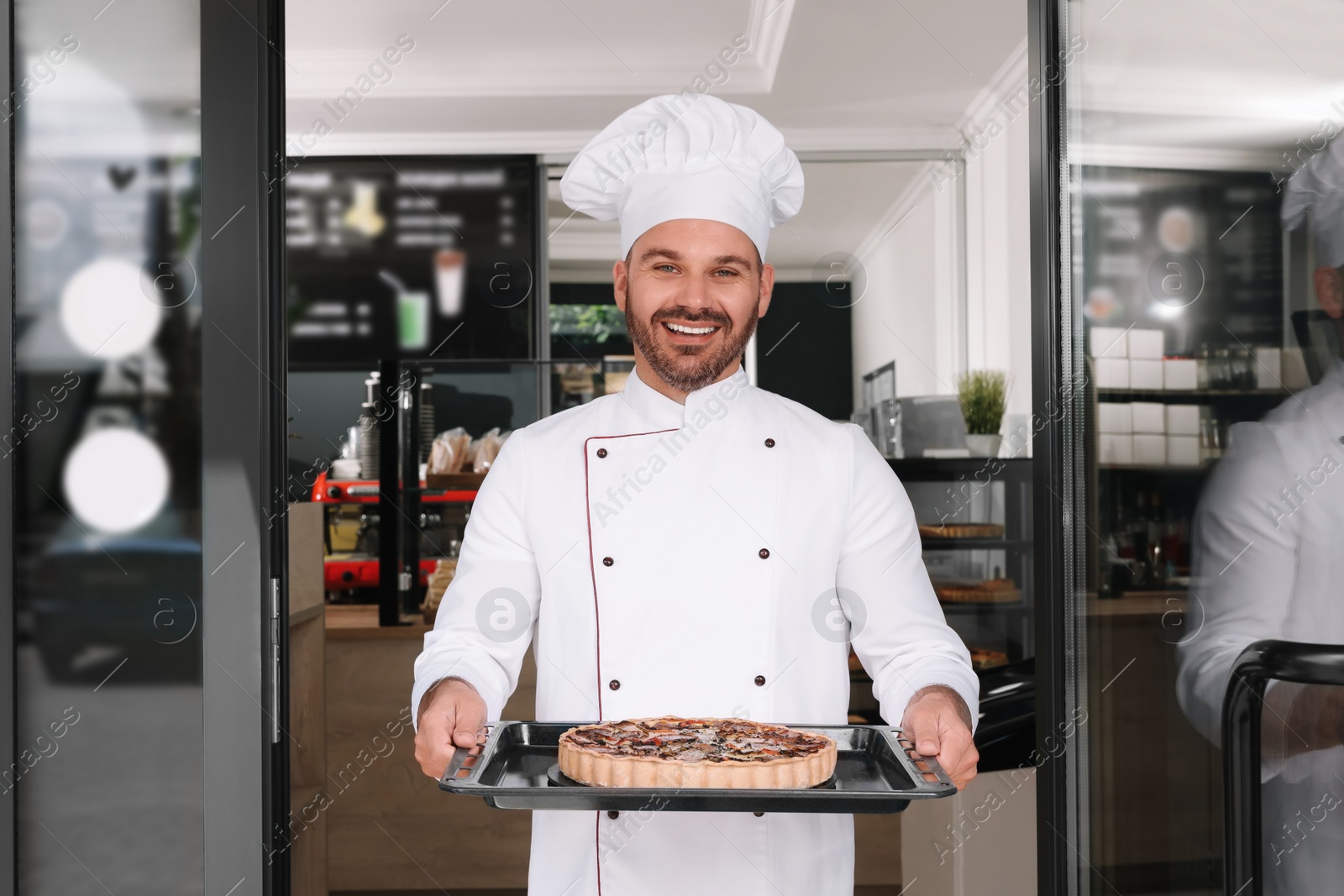 Photo of Happy baker presenting delicious quiche at door of his cafe
