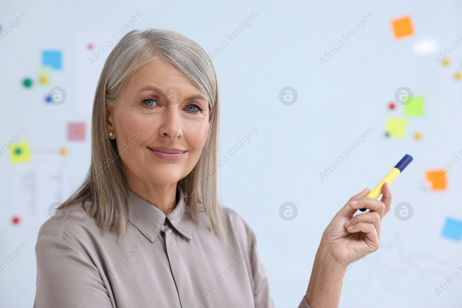 Photo of Portrait of happy professor with marker near whiteboard