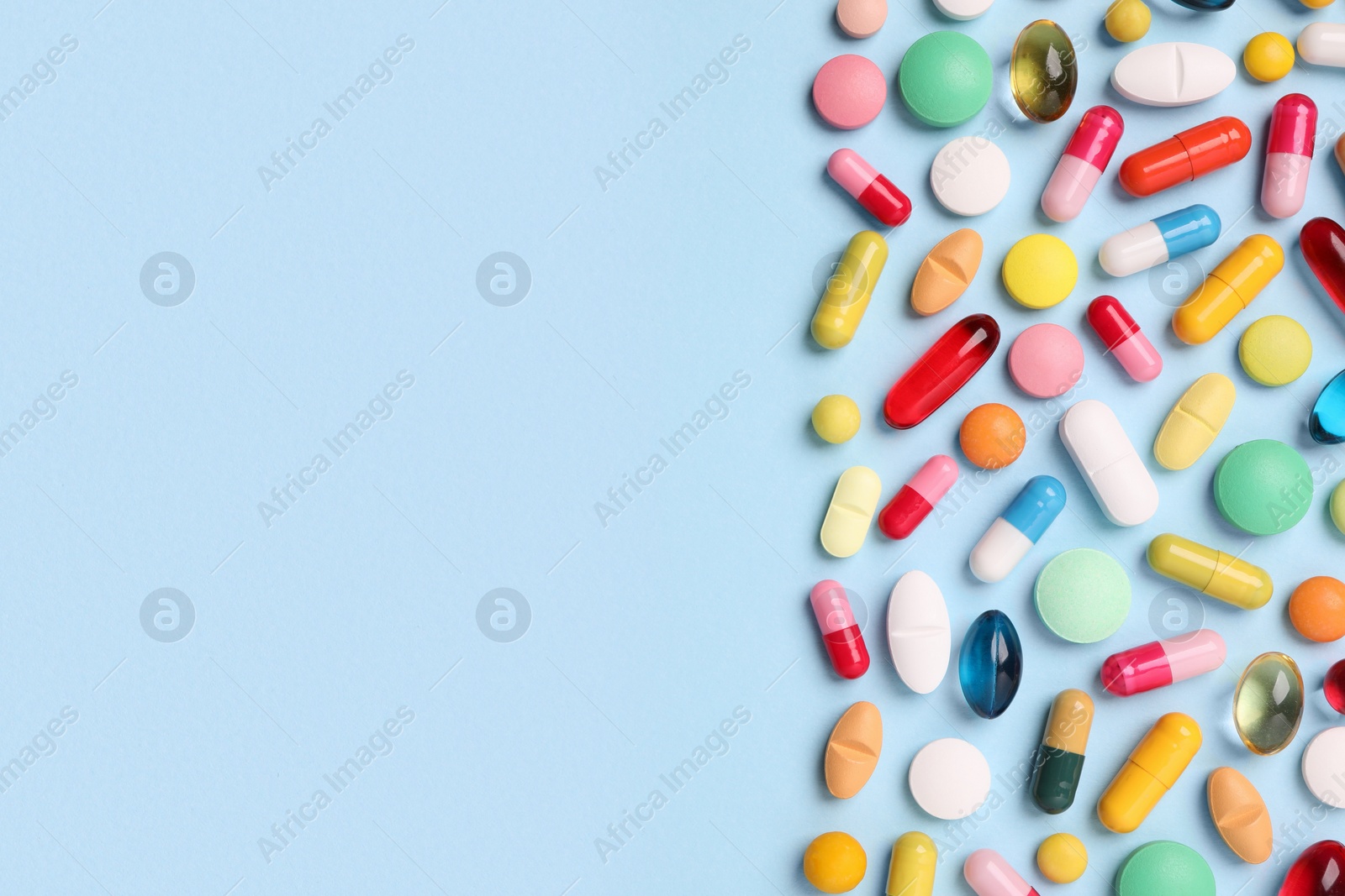 Photo of Many different pills on light blue background, flat lay. Space for text