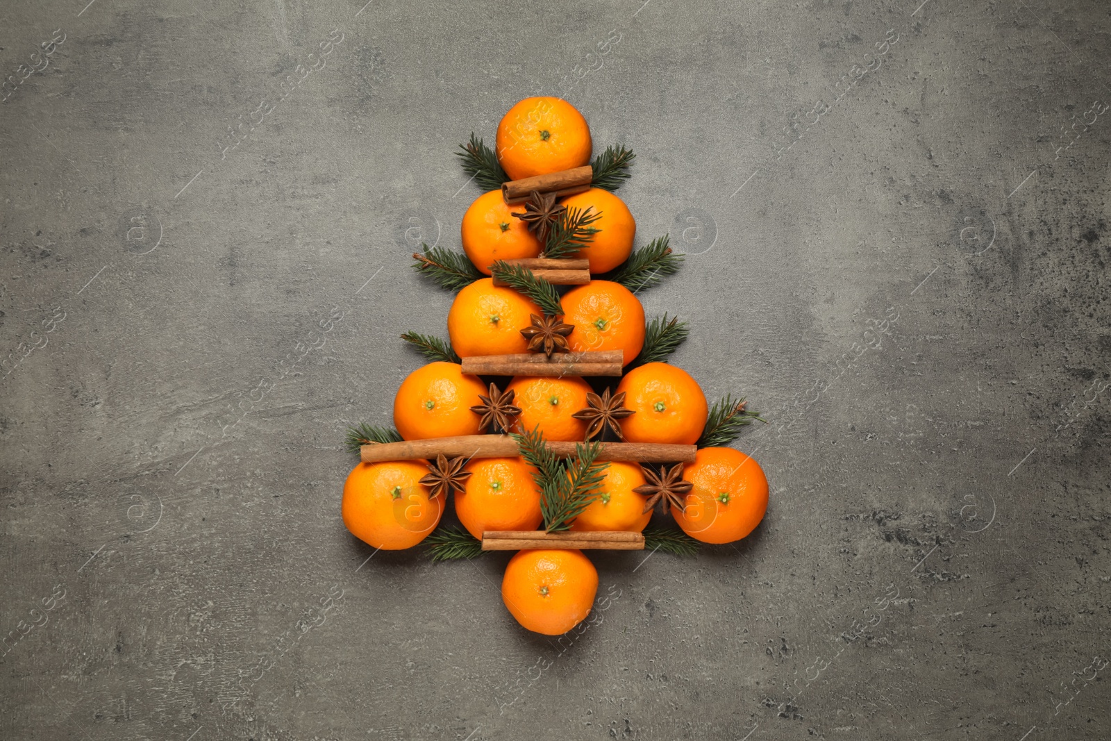 Photo of Christmas tree shape made of tangerines on grey background, flat lay