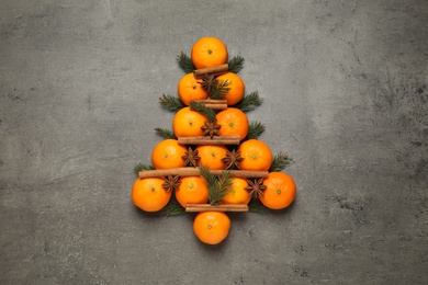 Christmas tree shape made of tangerines on grey background, flat lay