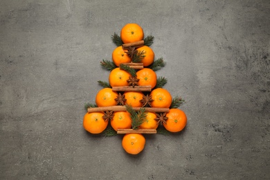 Photo of Christmas tree shape made of tangerines on grey background, flat lay