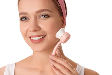 Photo of Young woman washing face with cleansing brush on white background. Cosmetic product