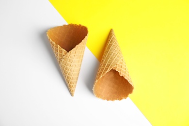 Empty wafer ice cream cones on color background, flat lay