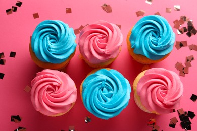 Photo of Delicious cupcakes with bright cream and confetti on pink background, flat lay