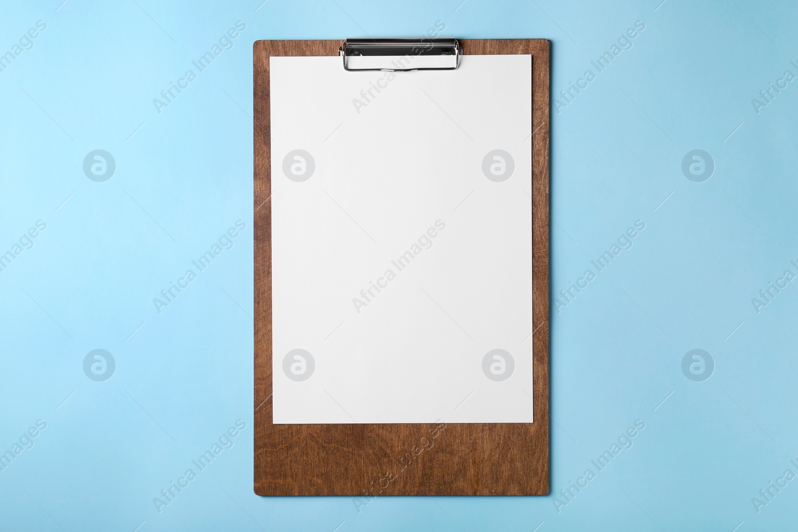 Photo of New wooden clipboard with sheet of blank paper on light blue background, top view