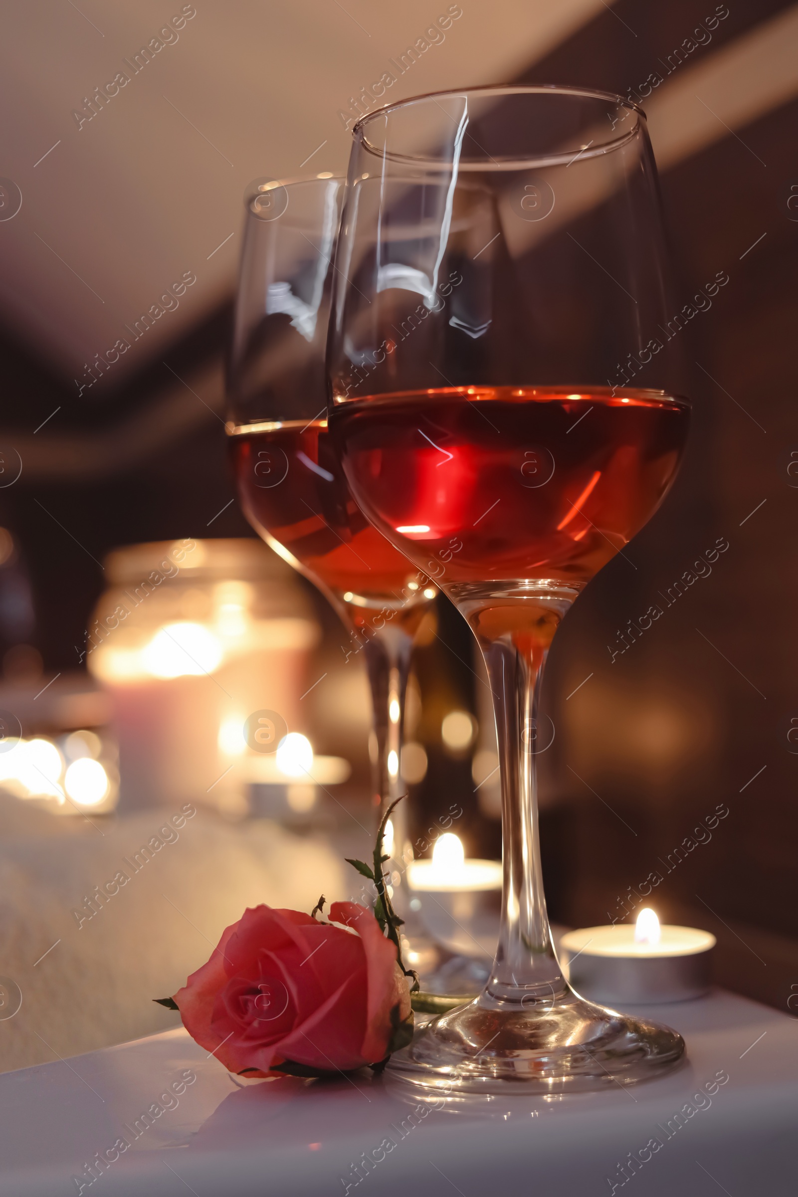 Photo of Glasses of wine and rose on tub in bathroom. Romantic atmosphere