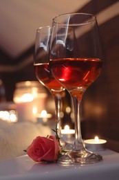 Photo of Glasses of wine and rose on tub in bathroom. Romantic atmosphere