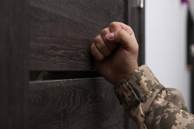 Photo of Military commissariat representative knocking on wooden door, closeup