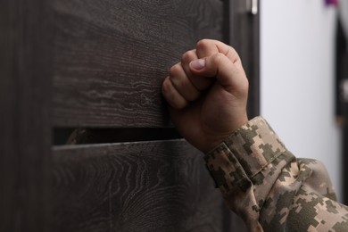 Military commissariat representative knocking on wooden door, closeup