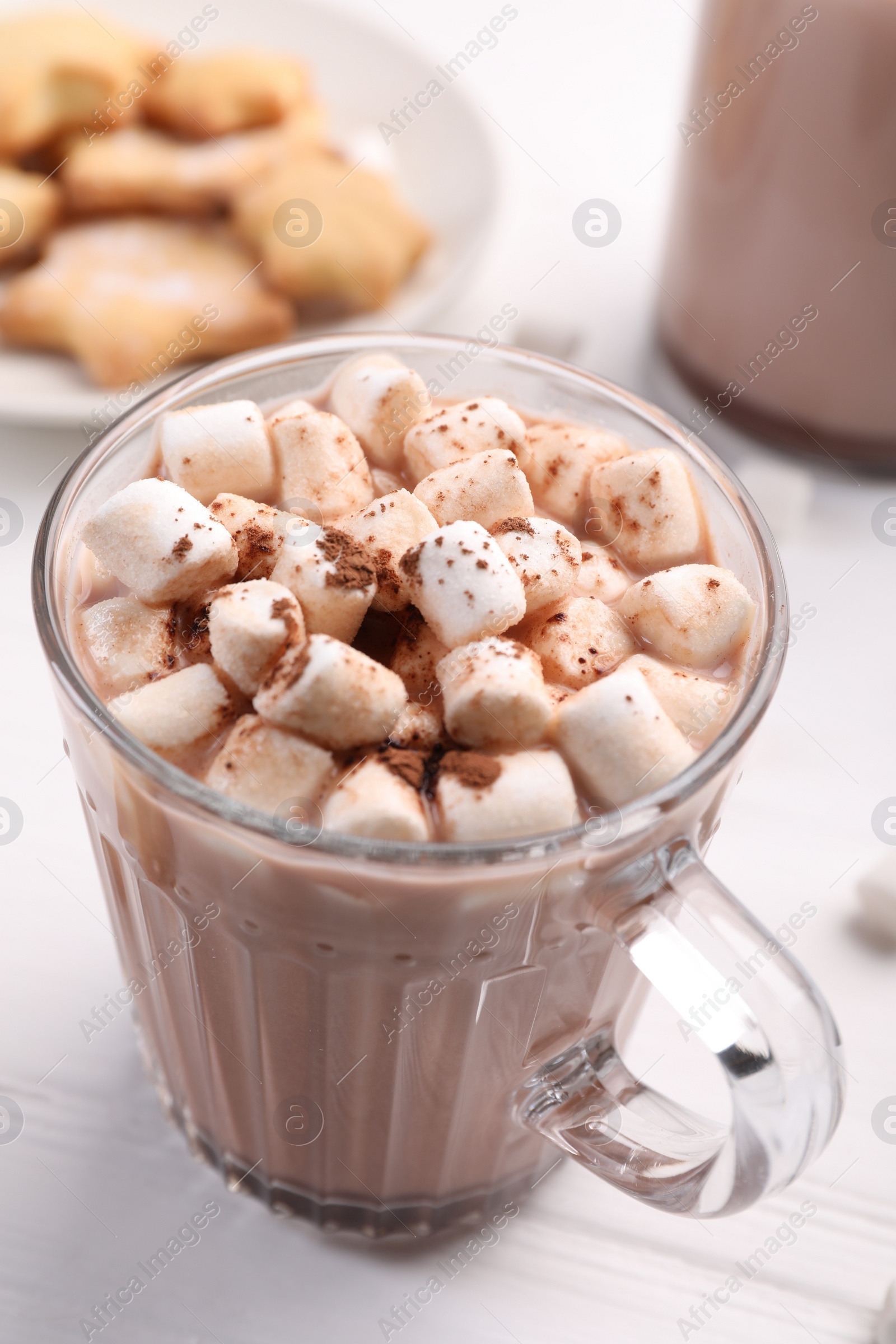 Photo of Cup of aromatic hot chocolate with marshmallows and cocoa powder on white table, closeup