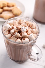 Photo of Cup of aromatic hot chocolate with marshmallows and cocoa powder on white table, closeup