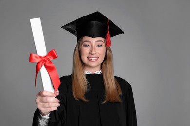Happy student with diploma on grey background