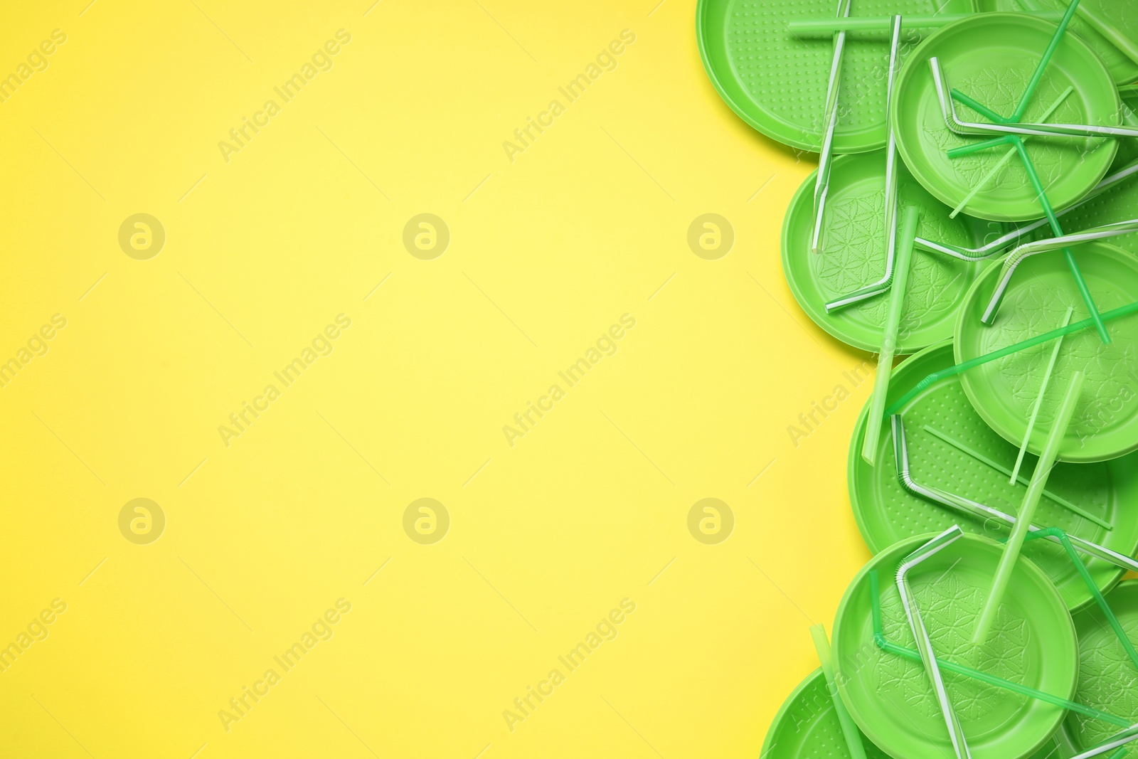 Photo of Plastic dishware on yellow background, flat lay. Space for text