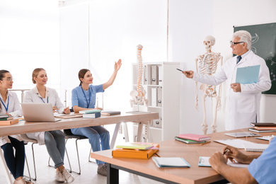 Photo of Medical students and professor studying human skeleton anatomy in classroom