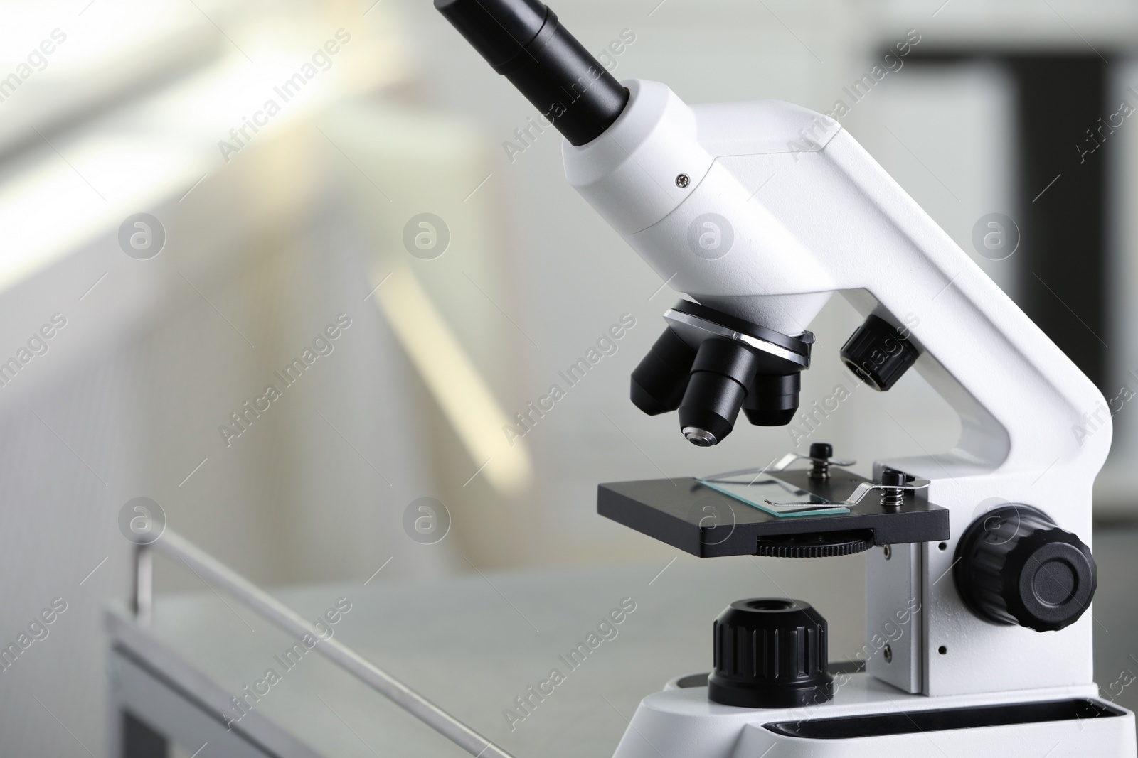 Photo of Modern medical microscope on metal table in laboratory, closeup. Space for text